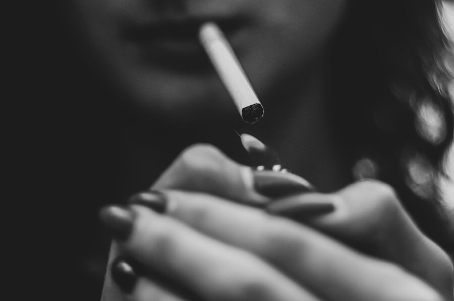 Žena si zapaľuje cigaretu
