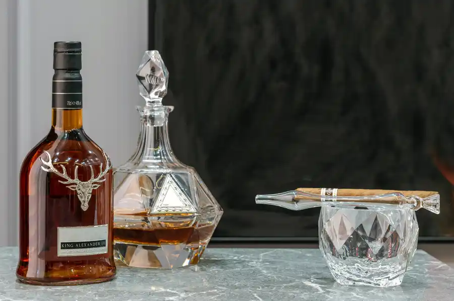 Kvalitný alkohol - fľaša, karafa a kryštálový pohár s cigarou