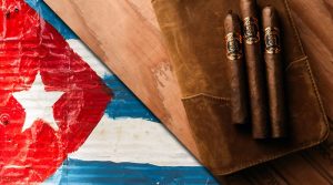 vlajka Kuby a cigary položené na koženom cestovnom humidore