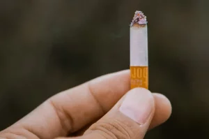 Detailný záber horiacej cigarety v mužských prstoch