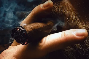 Fajčenie cigary - detail na muža s bradou, fajčiaceho cigaru