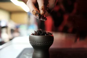 Nakladanie tabaku zvlhčeného melasou do keramickej korunky vodnej fajky