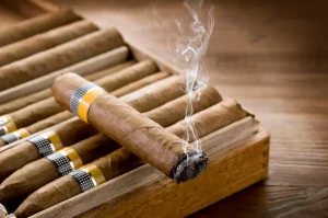 Horiaca cigara značky Cohiba položená na humidore