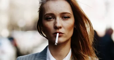 Mladá žena má v ústach zapálenú cigaretu - detailný záber hlavy a ramien