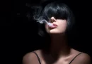 Mladá žena v tieni vydychuje z úst dym