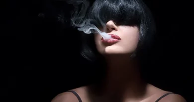 Mladá žena v tieni vydychuje z úst dym