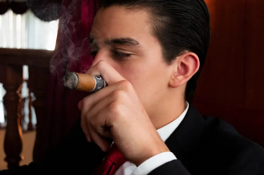 Mladý muž v obleku fajčí cigaru - detail