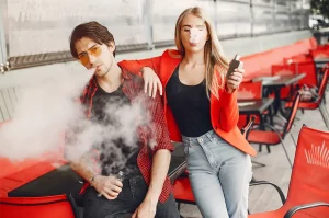 Pár mladej ženy a muža fajčí elektronickú cigaretu
