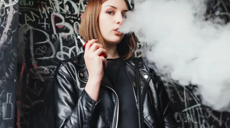 Mladá žena vydychuje paru z elektronickej cigarety