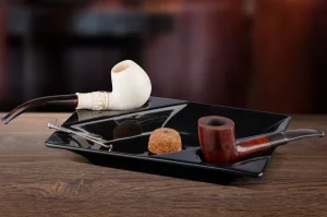 Fajka na tabak z morskej peny a z briaru odložené na čiernom fajkovom popolníku stojacom na drevenom stole
