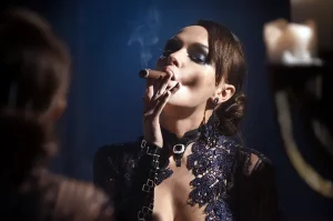 Mladá žena v elegantnom oblečení si poťahuje z cigary